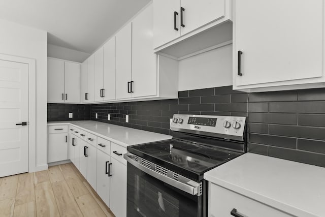 kitchen with white cabinetry, light wood-style floors, light countertops, tasteful backsplash, and stainless steel range with electric stovetop