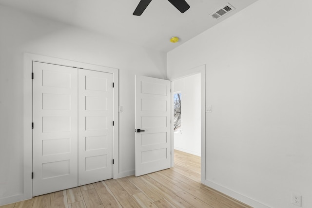 unfurnished bedroom featuring baseboards, light wood-style flooring, visible vents, and a closet