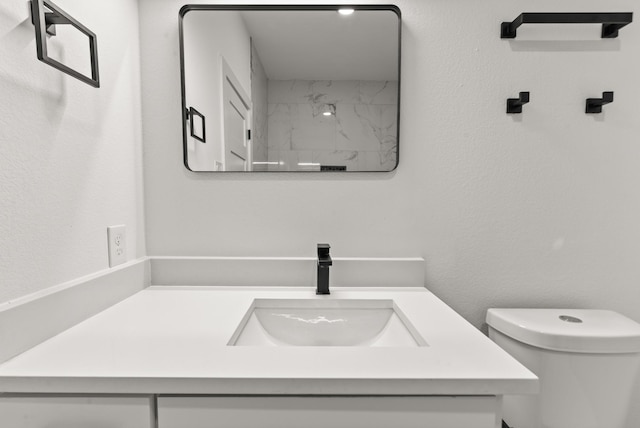 bathroom featuring a textured wall, vanity, and toilet