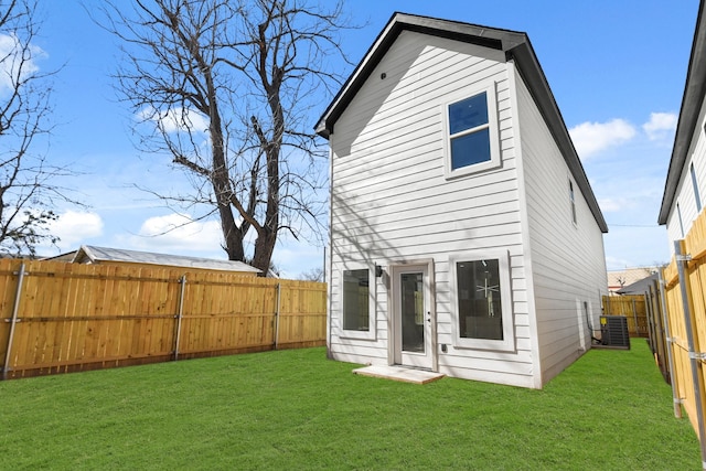 rear view of house featuring a fenced backyard, cooling unit, and a yard