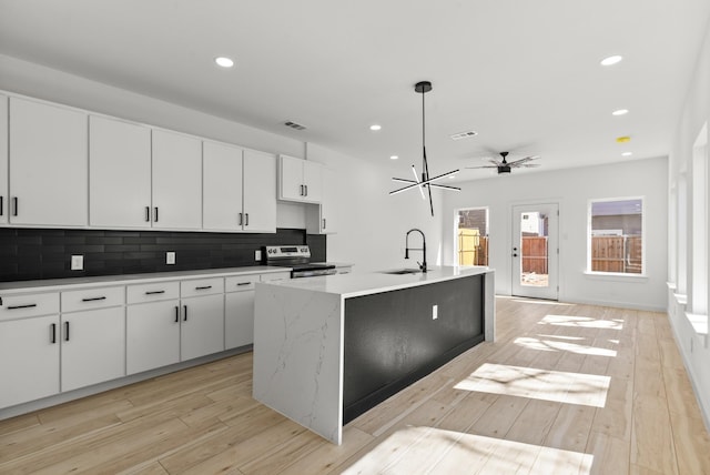 kitchen with tasteful backsplash, light wood-style floors, stainless steel electric range oven, and a sink