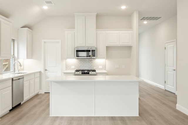 119 Emperor Oak Ct, Balch Springs, TX 75181 - kitchen with stainless steel appliances, a sink, backsplash, a center island, and light wood-style floors
