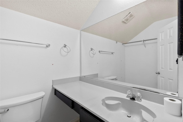 bathroom with vaulted ceiling, toilet, a textured ceiling, and vanity