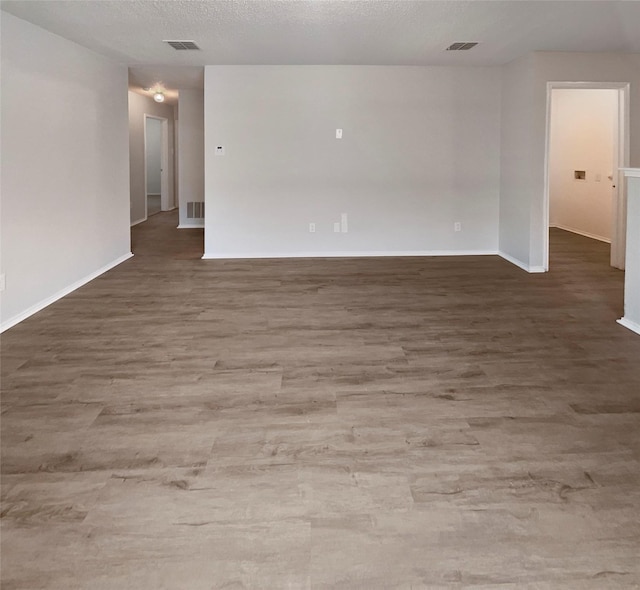 unfurnished room with visible vents, a textured ceiling, and wood finished floors