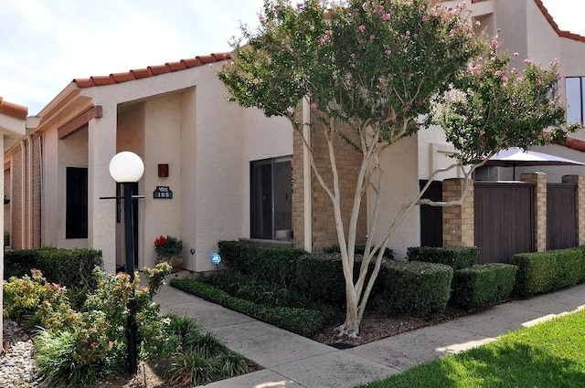 view of front of home with a tile roof, fence, and stucco siding