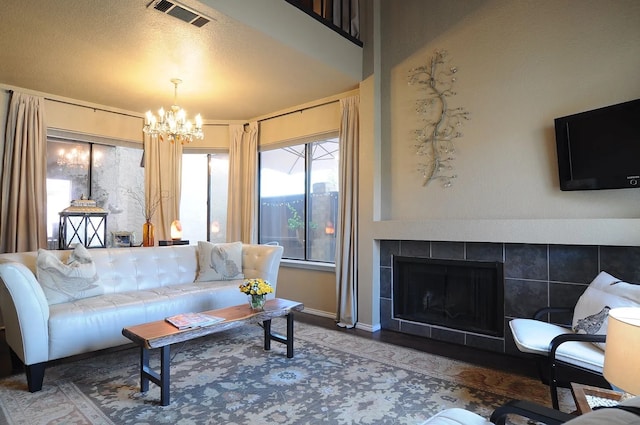 living area with a notable chandelier, visible vents, and a tiled fireplace