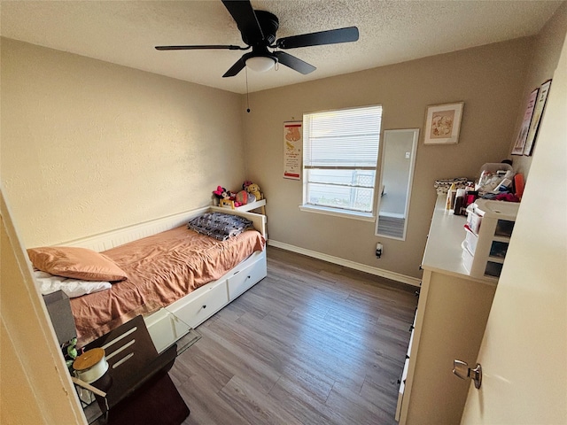 bedroom featuring a textured ceiling, ceiling fan, wood finished floors, and baseboards