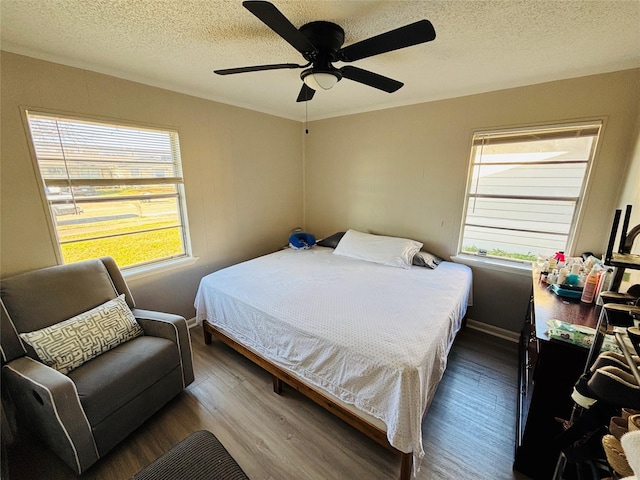 bedroom with a textured ceiling, ceiling fan, and wood finished floors