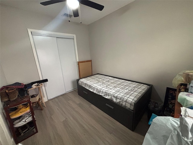 bedroom with ceiling fan, a closet, visible vents, and wood finished floors