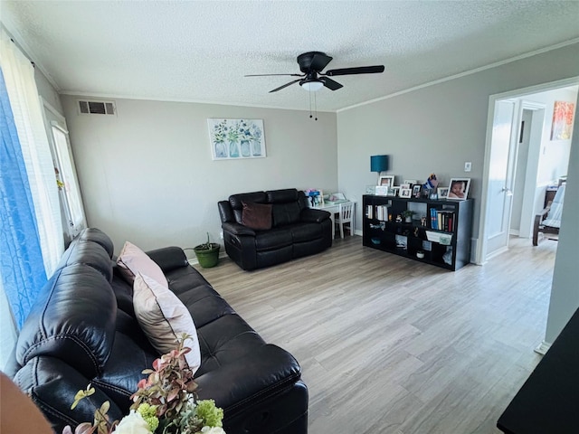 living room featuring crown molding, visible vents, a ceiling fan, a textured ceiling, and wood finished floors