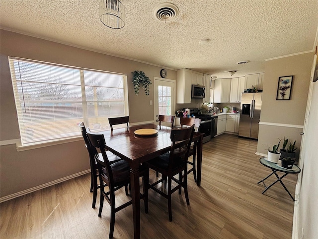 dining space featuring ornamental molding, visible vents, baseboards, and wood finished floors