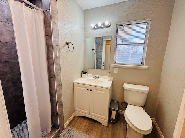 full bathroom with toilet, wood finished floors, vanity, baseboards, and a shower stall