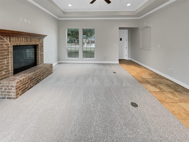 unfurnished living room featuring a fireplace, a raised ceiling, and baseboards