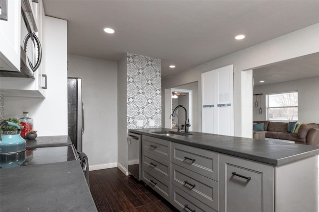 kitchen featuring white cabinets, dark countertops, appliances with stainless steel finishes, dark wood-style flooring, and a sink