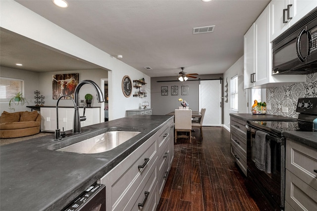 kitchen featuring visible vents, dark countertops, dark wood-style flooring, black appliances, and a sink