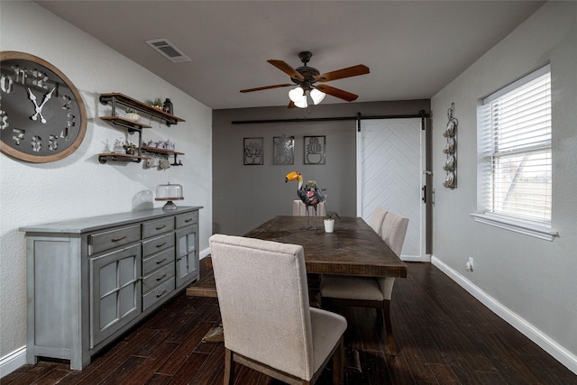 dining room featuring a barn door, visible vents, baseboards, dark wood-style floors, and ceiling fan