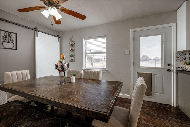 dining room featuring a textured wall, wood finished floors, ceiling fan, and a barn door