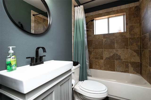 bathroom featuring a textured wall, vanity, shower / bath combo with shower curtain, and toilet