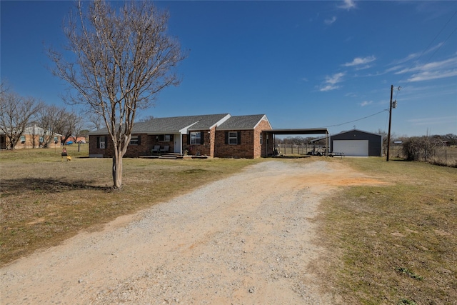 ranch-style home featuring driveway, brick siding, a front lawn, and an outdoor structure