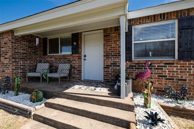 property entrance featuring a porch and brick siding