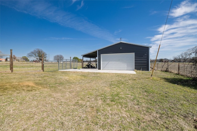 view of yard featuring an outbuilding, a garage, an outdoor structure, fence, and driveway