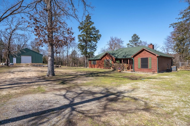 view of front of property featuring a garage, dirt driveway, a chimney, a porch, and central AC