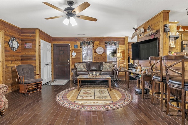 living room featuring visible vents, wood finished floors, a ceiling fan, and wooden walls