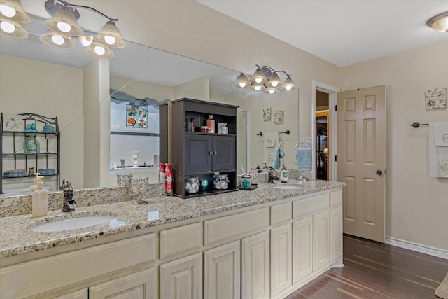 full bath with double vanity, a sink, baseboards, and wood finished floors