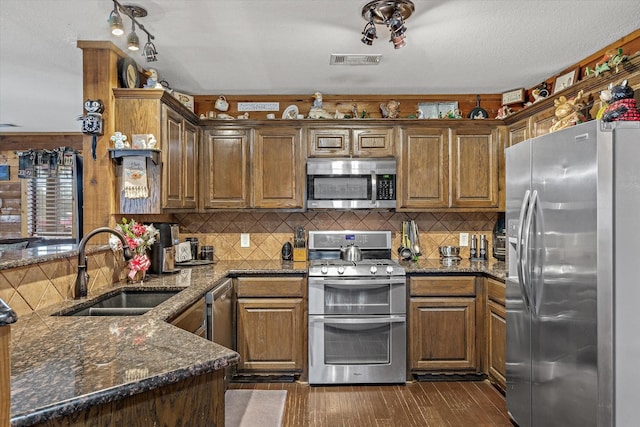 kitchen featuring visible vents, appliances with stainless steel finishes, dark wood-type flooring, a peninsula, and a sink