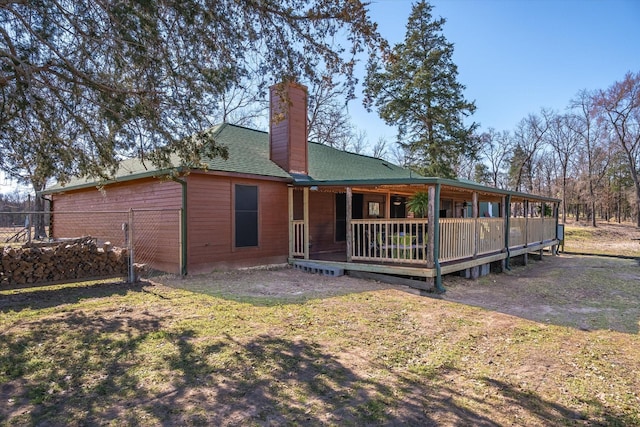 back of property with a chimney, fence, and roof with shingles