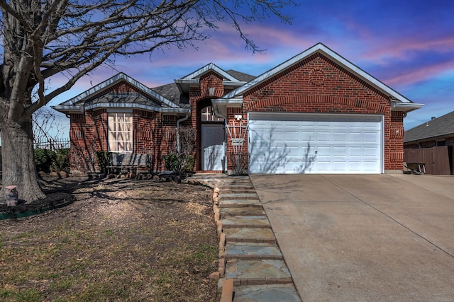 view of front of home featuring driveway, an attached garage, fence, and brick siding