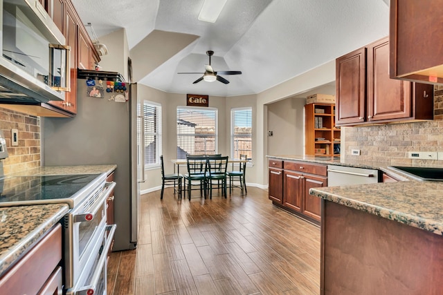 kitchen with light stone counters, appliances with stainless steel finishes, dark wood-type flooring, a ceiling fan, and a sink