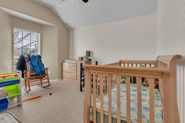 bedroom with carpet flooring, vaulted ceiling, a crib, and baseboards