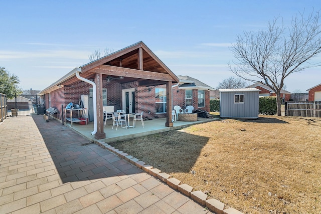 back of house with fence, an outdoor structure, a patio area, a shed, and brick siding