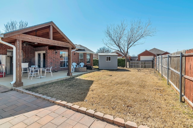 view of yard featuring a patio area, a storage shed, an outdoor structure, and a fenced backyard