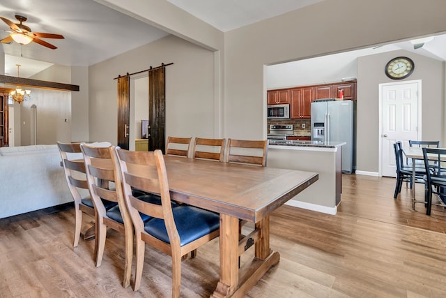 dining room featuring a barn door, baseboards, light wood-style flooring, and ceiling fan with notable chandelier