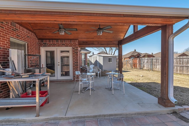 view of patio featuring a storage shed, a fenced backyard, a ceiling fan, and an outbuilding