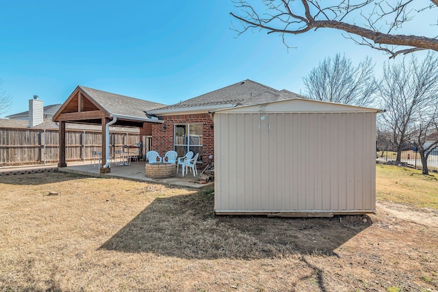 exterior space featuring brick siding, a patio area, a fenced backyard, and a shingled roof