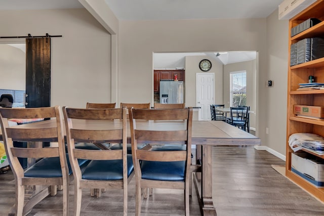 dining space featuring a barn door, wood finished floors, and baseboards