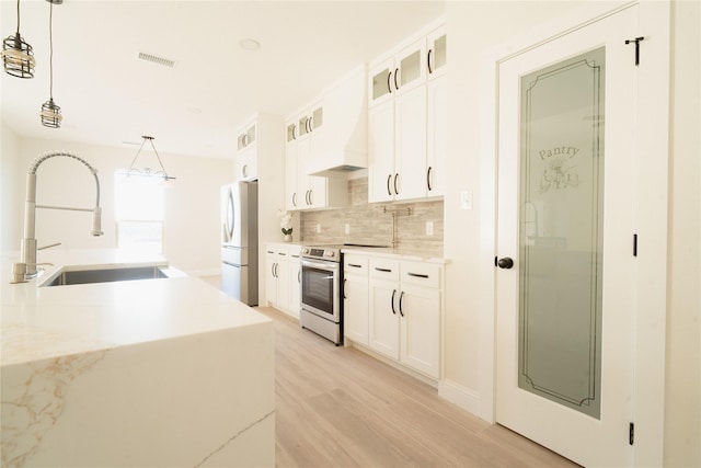 kitchen with electric range, a sink, visible vents, freestanding refrigerator, and tasteful backsplash