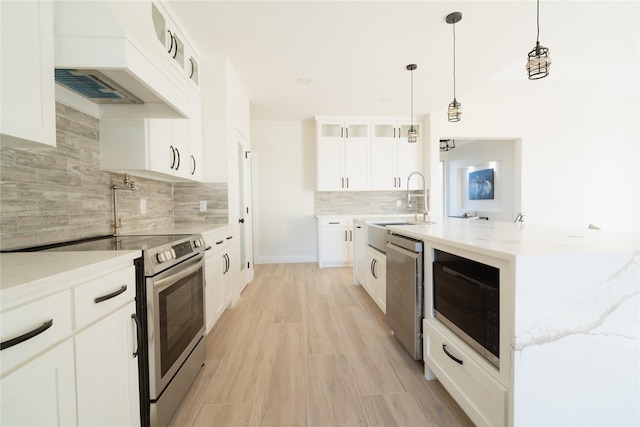 kitchen with stainless steel appliances, light wood-style floors, custom exhaust hood, light stone countertops, and glass insert cabinets