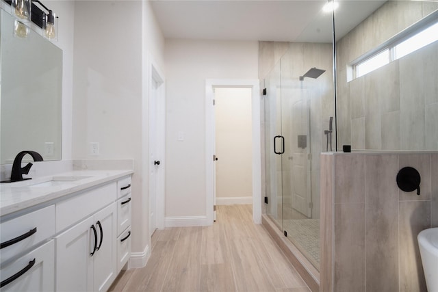 bathroom with a stall shower, vanity, and baseboards