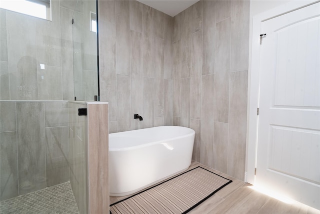 bathroom featuring a freestanding bath, a tile shower, and tile walls