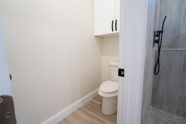 full bath with a stall shower, wood finished floors, toilet, and baseboards