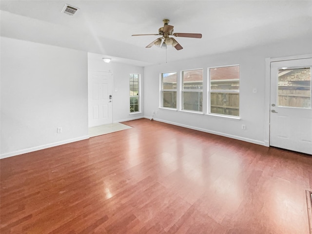 unfurnished room with a ceiling fan, visible vents, baseboards, and wood finished floors