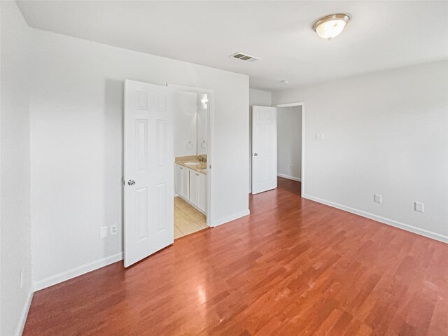 spare room with light wood-type flooring, visible vents, and baseboards