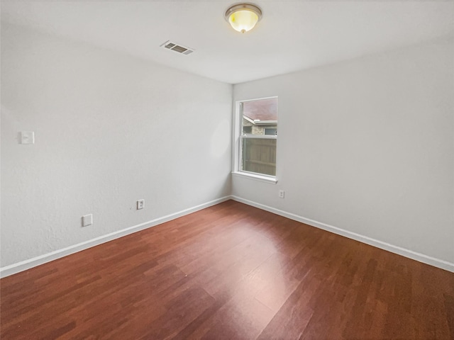 unfurnished room featuring wood finished floors, visible vents, and baseboards
