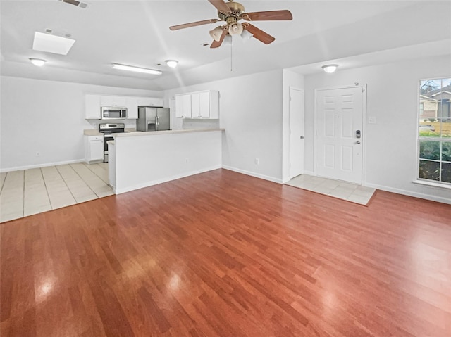 unfurnished living room featuring light wood-type flooring, ceiling fan, and baseboards