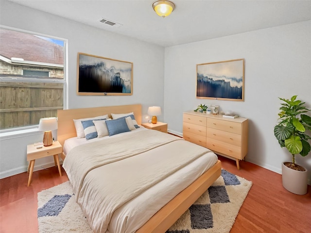 bedroom with light wood-style flooring, visible vents, and baseboards