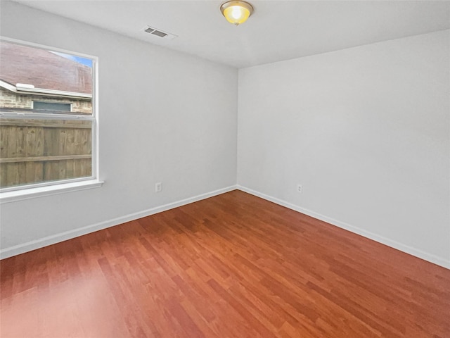 empty room with visible vents, baseboards, and wood finished floors
